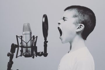 Black and white image of a boy shouting into a podcast microphone